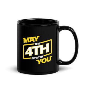 Könnte beinhalten: Schwarze Keramiktasse mit einer gelben und weißen Grafik, auf der "Möge die 4. mit dir sein" steht.