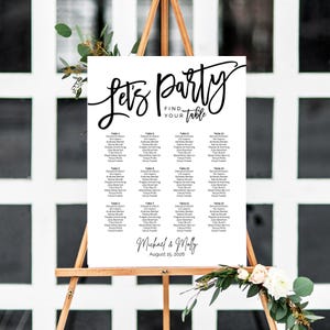 May include: A black and white wedding seating chart with the text "Let's Party Find Your Table" at the top. The chart lists tables 1 through 14 with guest names for each table. The chart also includes the names "Michael & Molly" and the date "August 15, 2026".