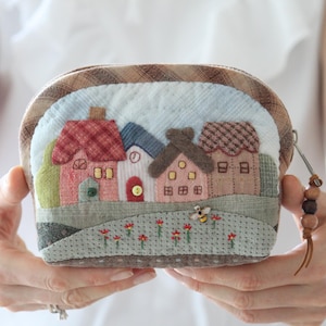 Trousse de maquillage zippée avec maisons. Étui de voyage matelassé. Sac en patchwork japonais orné d'un pendentif en bois.