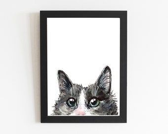 May include: Watercolor painting of a cat's face, framed in black. The cat has gray and white fur, with bright green eyes and a pink nose. The artwork is a close-up of the cat's face, with only the eyes and ears visible.