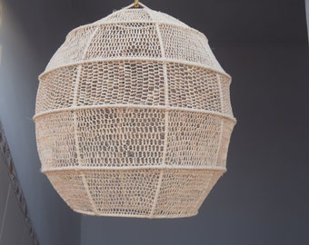 May include: A round, beige, woven pendant light fixture with a geometric design. The light fixture is made of natural materials and has a rustic, bohemian style.
