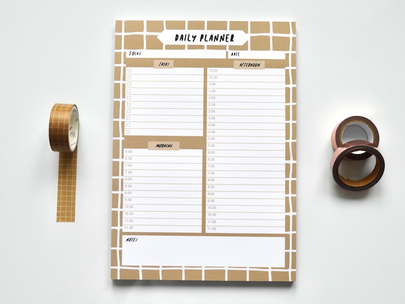 May include: A brown daily planner with a grid pattern and the words "DAILY PLANNER" at the top. The planner has sections for "Focus", "Tasks", "Morning", "Afternoon", and "Notes".