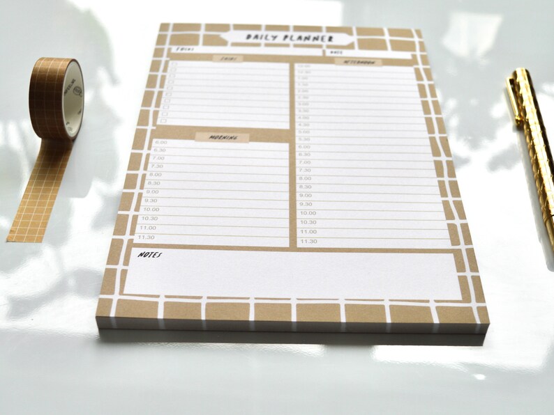 May include: A brown daily planner with a grid pattern and white lines. The planner has a section for "Morning" and "Afternoon" with time slots from 8:00 AM to 11:30 AM. The planner also has a section for "Notes".
