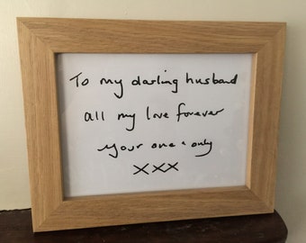 May include: A light-colored wooden frame containing a white rectangular insert with black handwritten text that reads: To my darling husband, all my love forever, your one & only, XXX.