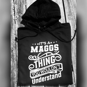 May include: Black hooded sweatshirt with white text that reads "It's a Maggs Thing You Wouldn't Understand".