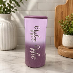 May include: A cylindrical tumbler with a purple ombre glitter finish, featuring a solid purple lid and the text "Wee Wee" in a silver script font vertically centered on the front surface of the container.