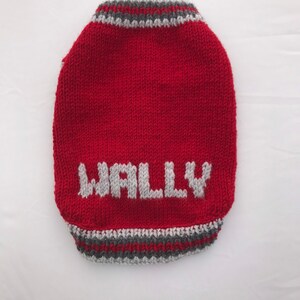 Pu&ograve; includere: Maglia di lana rossa per cani con bordini grigi e il nome "Wally" lavorato a maglia in bianco.