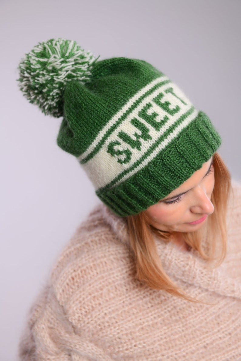 May include: Green knitted beanie with a white pom pom and a white stripe with the word "SWEET" in green letters.