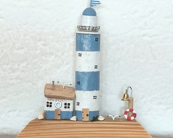 Handgefertigtes Holzhaus. Mini-Küstenszene mit Holzhütte und Leuchtturm. Treibholz-Miniatur-Seedorf.