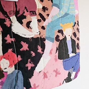 Pu&ograve; includere: Borsa tote trapuntata con un colorato design astratto con figure in varie pose. La borsa ha una combinazione di colori rosa, nero e marrone con un'etichetta che recita "Let's Picnic". Il design include forme di stelle rosa.