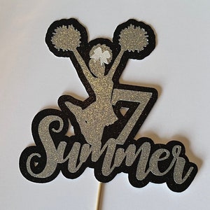 May include: Black and silver glitter cake topper with a cheerleader silhouette holding pom-poms and the word "Summer".