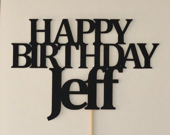 May include: Black glitter cake topper with the text "Happy Birthday Jeff" in a layered, staggered design.