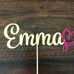 May include: Gold glitter cake topper with the name "Emma" and a pink glitter heart.