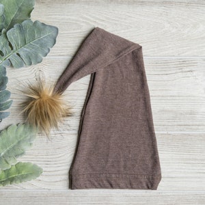 May include: A brown knit elf hat with a long pointed top and a fluffy brown pom pom.