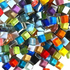 May include: A collection of over 200 colorful crystal mosaic glass pieces. The small, square tiles are in various colors, including red, blue, yellow, green, and purple. The image includes an arrow pointing to the text "200+ "CRYSTAL" MOSAIC GLASS PIECES."