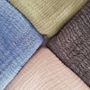 May include: An overhead shot of four folded fabric squares in a diamond arrangement. The fabrics are in shades of blue, green, gray, and beige. The fabric has a textured, woven appearance.