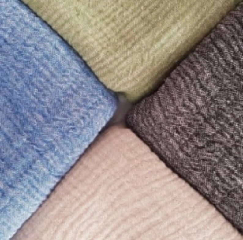 May include: An overhead shot of four folded fabric squares in a diamond arrangement. The fabrics are in shades of blue, green, gray, and beige. The fabric has a textured, woven appearance.