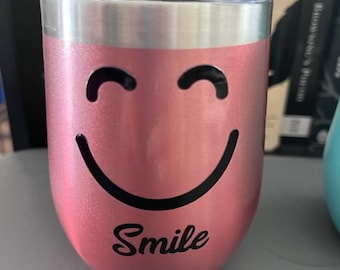 May include: A pink stainless steel tumbler with a black smiley face and the word "Smile" printed on the side.