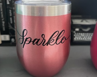 May include: A rose gold stainless steel tumbler with a black inscription that reads "Sparkle".