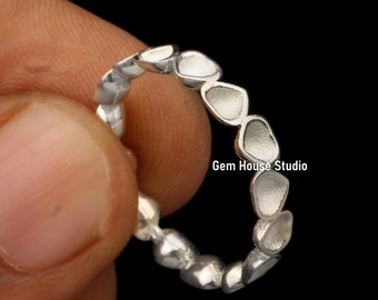 May include: A silver ring with a repeating pattern of irregular, petal-shaped designs. The ring is held against a black background. The text "Gem House Studio" is visible on the image.