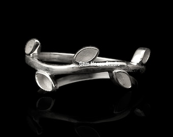 Könnte beinhalten: Ein silberner Ring mit einem zarten Zweigdesign mit vier Blättern. Der Ring ist aus poliertem Metall gefertigt und hat eine glatte, abgerundete Oberfläche.