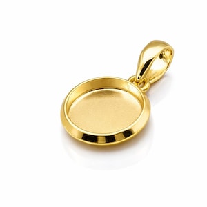 May include: A gold-colored pendant with a circular bezel setting. The pendant has a loop for a chain and a polished finish. The setting is designed to hold a small, round object, such as a gemstone or a photo.