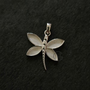 Peut inclure: Pendentif en argent en forme de libellule avec des ailes détaillées et un corps texturé. Le pendentif a une boucle en haut pour l'attacher à une chaîne.