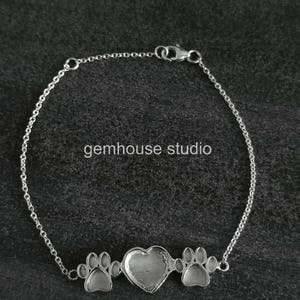 Op de afbeelding: Een zilverkleurige armband met een hartvormig middelpunt en pootafdrukbedels. De armband heeft een delicaat kettingontwerp en een sluiting. De tekst "gemhouse studio" is zichtbaar op de afbeelding.