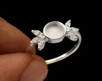 Op de afbeelding: Zilveren ring met een ronde bezel-setting en twee blaadjes aan weerszijden. De bezel is leeg en klaar om te worden gevuld met een steen of ander materiaal.