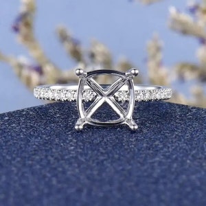 May include: A silver ring setting with a round center stone and a pave diamond band.