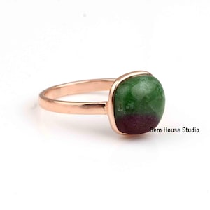 Peut inclure: Une bague en or rose avec une pierre précieuse verte et violette. La bague est sertie dans un sertissage à  bezel et a une finition lisse et polie.