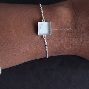 Puede incluir: Un brazalete de cadena de plata con un colgante de forma cuadrada. El colgante está en blanco y listo para ser personalizado.