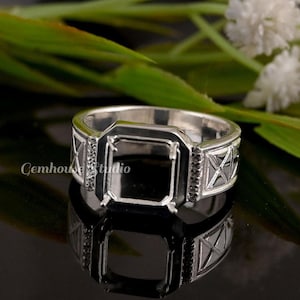 May include: A silver ring with a rectangular black setting. The ring has a geometric design on the sides and small black stones. The Gemhouse Studio logo is visible on the side of the ring.