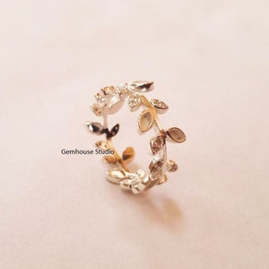 May include: Silver ring featuring a delicate design of leaves and small clear stones. The ring is open and adjustable.