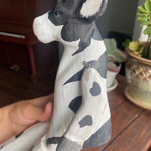 Hand carved wooden cow  with jointed legs, handheld, closeup of side profile