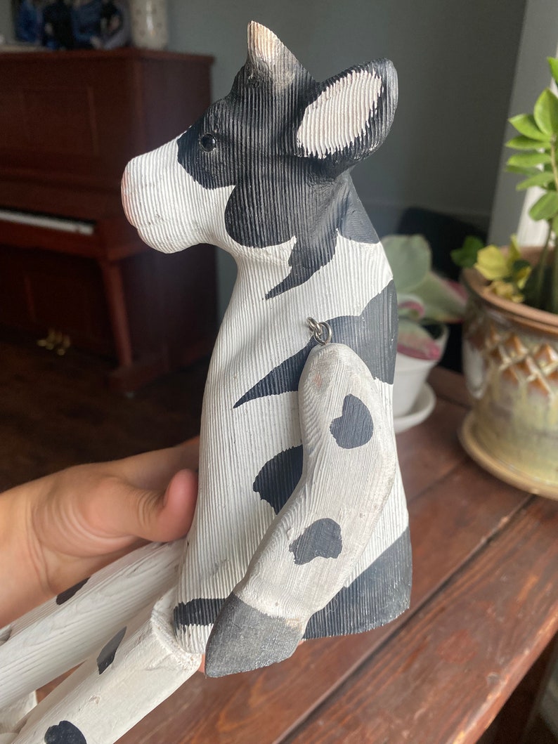Hand carved wooden cow  with jointed legs, handheld, closeup of side profile