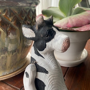 Hand carved wooden cow  with jointed legs sitting on shelf, closeup of face