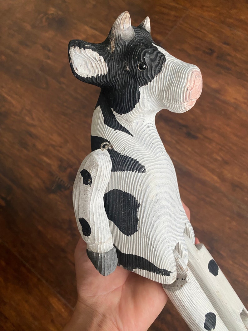 Hand carved wooden cow  with jointed legs sitting on palm of hand