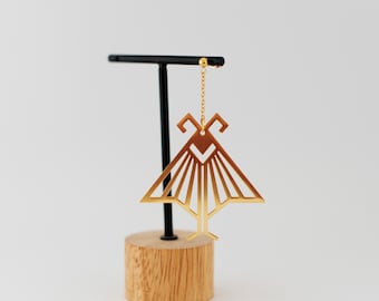 May include: Gold geometric dangle earring with a triangular shape and a delicate chain. The earring is displayed on a wooden stand.
