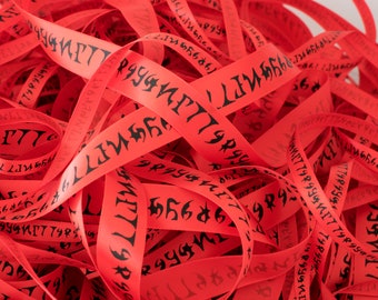 May include: A pile of red satin ribbon with black printed runes. The ribbon is tangled and overlapping.