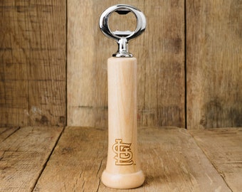 May include: A wooden bottle opener shaped like a baseball bat with the St. Louis Cardinals logo.