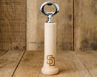 May include: A wooden bottle opener with a silver bottle opener on top. The bottle opener has the San Diego Padres logo engraved on the side.