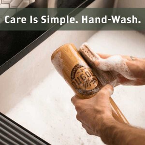 Puede incluir: Un mug de madera con forma de bate de b&eacute;isbol se lava con una esponja en un fregadero. El mug tiene las palabras "Dugout Mug" impresas.