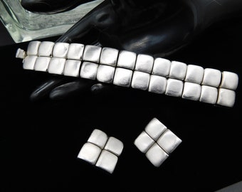 Puede incluir: Un conjunto de pulsera y pendientes de plata con un diseño geométrico cuadrado. La pulsera está hecha de múltiples eslabones cuadrados y los pendientes están hechos cada uno de cuatro cuadrados.