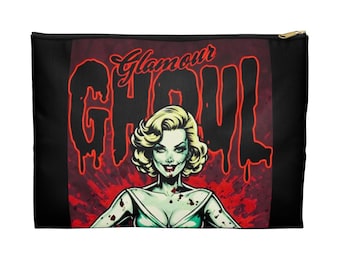 Op de afbeelding: Zwarte make-up tas met een gouden rits, met een afbeelding van een zombie vrouw met blond haar en de woorden "Glamour Ghoul" in het rood. De achtergrond is rood met bloedspatten.