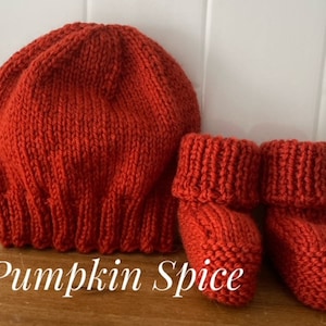 May include: A knitted pumpkin spice colored baby hat and matching booties. The hat is a round, ribbed design. The booties have a folded cuff. The text "Pumpkin Spice" is at the bottom of the image.