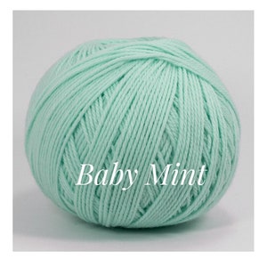 May include: A ball of Baby Mint yarn, a soft, light green color. The yarn is tightly wound, showing the texture of the individual strands. The text "Baby Mint" is printed on the yarn.