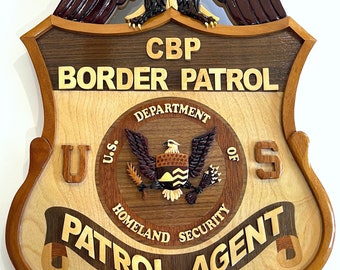 May include: A wooden plaque with a carved eagle, the words "CBP Border Patrol", a seal with the words "U.S. Department of Homeland Security", and the words "Patrol Agent". The plaque measures 50.8 cm by 33 cm.