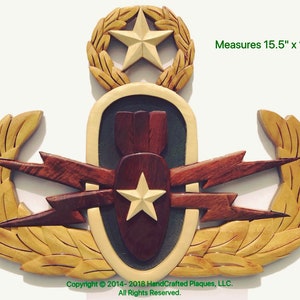 May include: A wooden plaque featuring a military emblem with a star, bomb, and lightning bolt design. The plaque is made of various wood tones and measures 15.5" x 12". Copyright 2014-2018 HandCrafted Plaques, LLC.