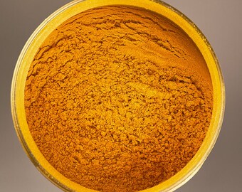 May include: A close-up view of a bowl filled with bright yellow turmeric powder.